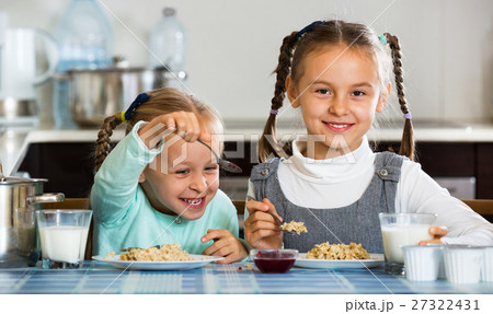 Two small cheerful girls eating healthy oatmeal 27322431