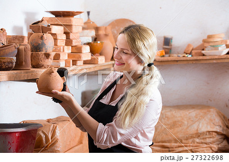 Positive woman potter carrying ceramic vessels 27322698