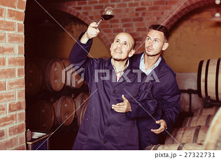 two winemakers with sample of wine in cellar. two winemakers with sample of wine in cellar. 27322731