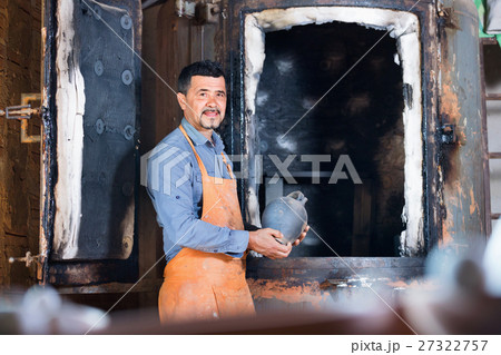 Cheerful craftsman carrying fresh baked black glazed vessel Cheerful craftsman carrying fresh baked black glazed vessel 27322757