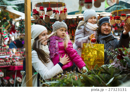 Smiling cheerful family of four buying Caga Tio. Focus on woman 27323131