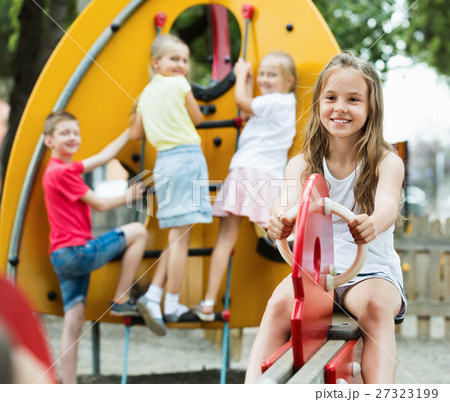 Smiling girl sitting on swing on children's playground 27323199