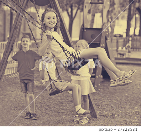 View on children swinging together on children's playground View on children swinging together on children's playground 27323531