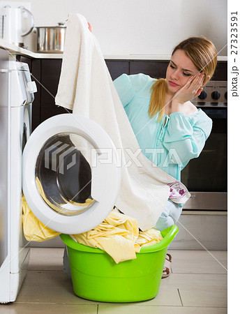 Upset young woman cannot remove stains off bed linen Upset young woman cannot remove stains off bed linen 27323591