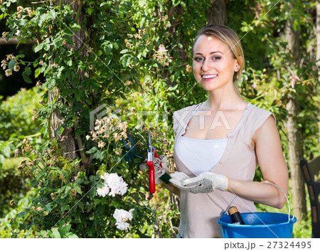 smiling young woman holding horticultural tools in garden smiling young woman holding horticultural tools in garden 27324495