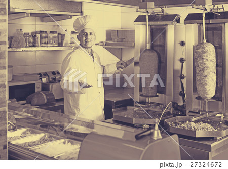 man chef wearing uniform cutting meat for kebab on kitchen in fa 27324672