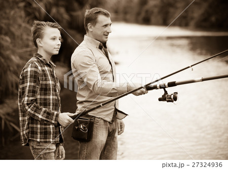 Man and boy fishing on freshwater lake from shore 27324936