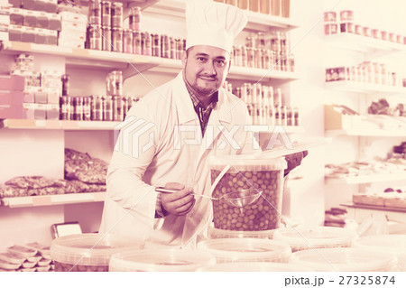 Shop staff standing near containers with olives in flavoured brine 27325874