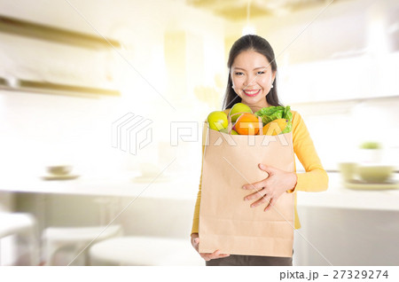 Woman holding groceries bag in kitchen 27329274