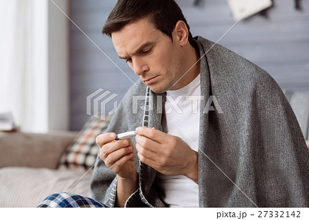 Unhappy ill man looking at the thermometer 27332142