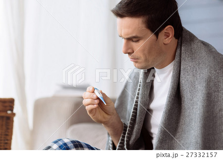 Sad unhappy man holding a thermometer Sad unhappy man holding a thermometer 27332157