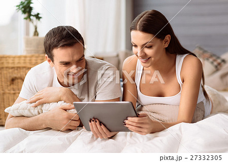 Pleasant positive couple looking at the tablet Pleasant positive couple looking at the tablet 27332305