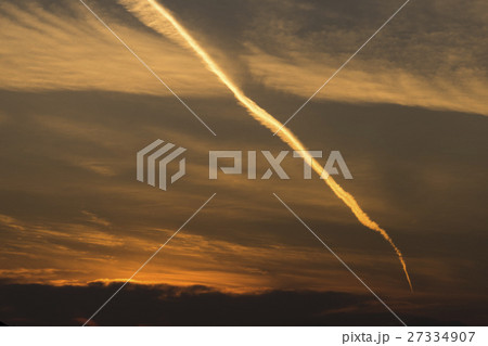 朝焼けと日の出の朝日に映える飛行機雲始発着陸軌跡 27334907