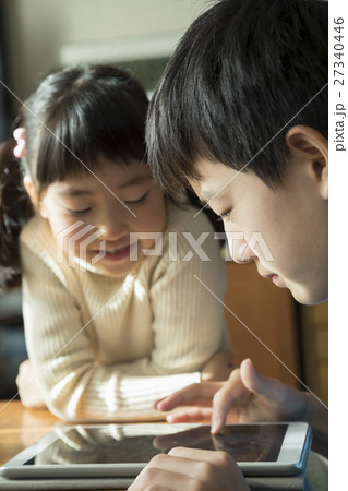 仲良くタブレットゲームで遊ぶ兄妹 27340446