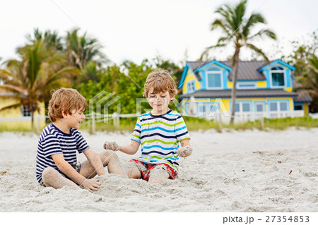 Two kid boys building sand castle on tropical Two kid boys building sand castle on tropical 27354853
