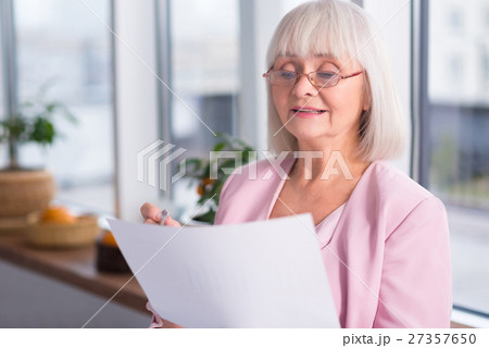 Serious businesswoman examining a document Serious businesswoman examining a document 27357650