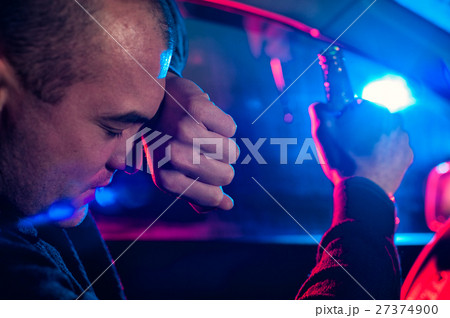 Drunk driver covering face from police car light 27374900