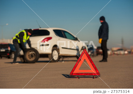 Car assistance repairman changing spare wheel 27375314