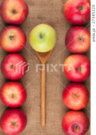 Spoon with green apple lying on the red apples 27385220