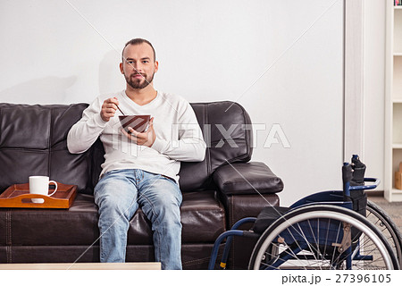 Positive disabled man having cereal in the living Positive disabled man having cereal in the living 27396105