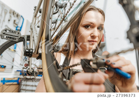 Charismatic female mechanic refitting the bicycle 27396373