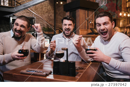 Cheerful jubilant friends watching a football Cheerful jubilant friends watching a football 27397042
