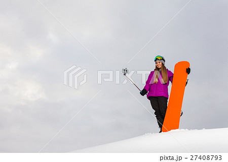 Young woman with the snowboard shooting a selfie  27408793