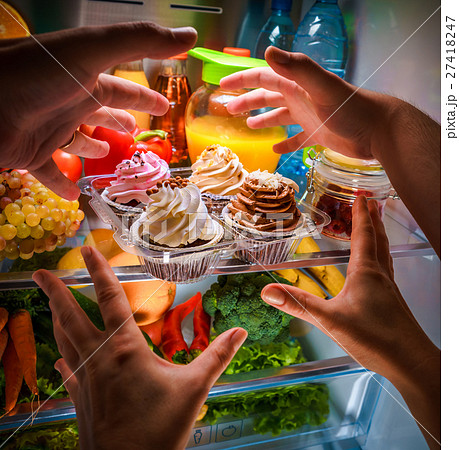 Human hands reaching for sweet cake at night  27418247