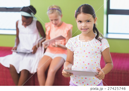 Schoolgirl holding digital tablet in library 27425746