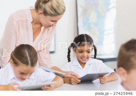 Teacher teaching school girl on digital tablet 27425946