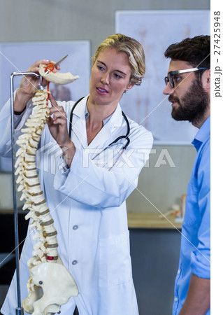 Physiotherapist explaining the spine model to patient 27425948