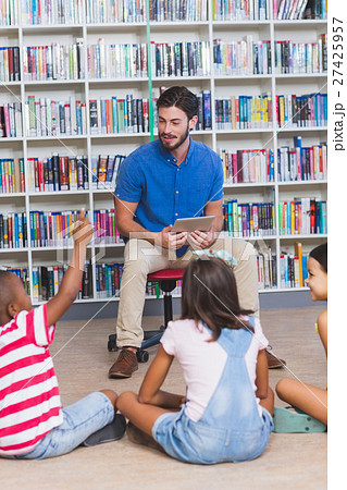 Teacher teaching kids on digital tablet in library Teacher teaching kids on digital tablet in library 27425957