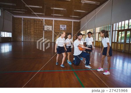 Sports teacher teaching school kids to play basketball 27425966