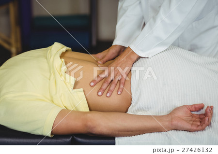 Female physiotherapist giving back massage to male patient 27426132