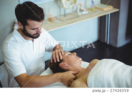 Portrait of smiling physiotherapist sitting with spine model 27426359