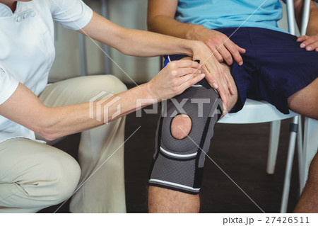 Physiotherapist examining patients knee Physiotherapist examining patients knee 27426511