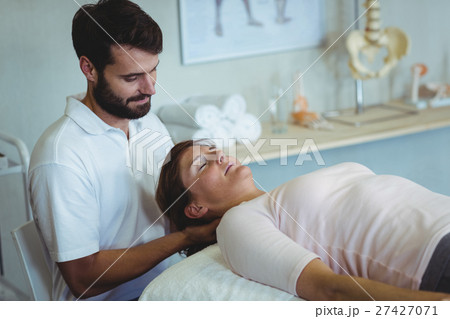 Physiotherapist giving neck massage to a woman 27427071