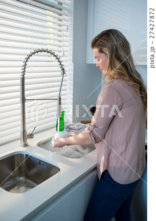 Woman washing bowl under sink in kitchen Woman washing bowl under sink in kitchen 27427872