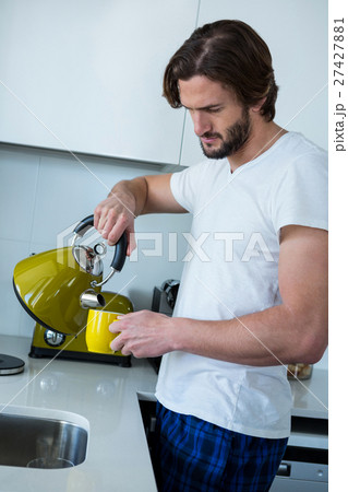 Man pouring coffee into cup in kitchen Man pouring coffee into cup in kitchen 27427881
