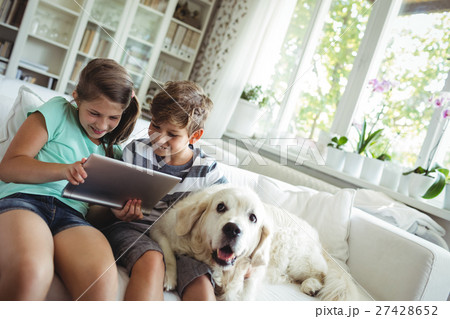 Children using digital tablet while sitting on a sofa 27428652