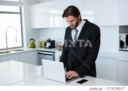 Businessman using laptop in kitchen 27429017