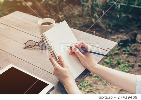 Close up hand woman writing notebook on wood table Close up hand woman writing notebook on wood table 27439409