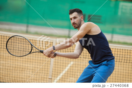 Happy young man playing on tennis clay court. 27440368