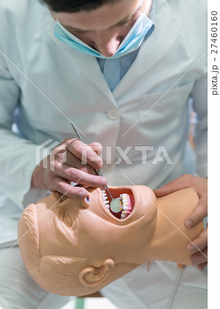 Male dental student practicing on doll. 27460160