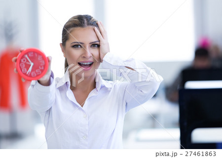 Businesswoman with clock being late for her Businesswoman with clock being late for her 27461863