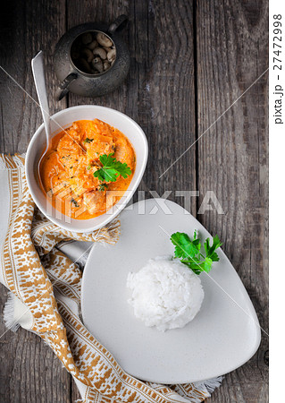 Chicken curry and rice served on a wooden surface. 27472998