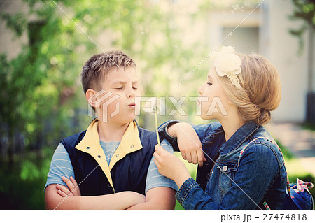 Young Boy and Girl Blowing a Dandelion Flowers Young Boy and Girl Blowing a Dandelion Flowers 27474818