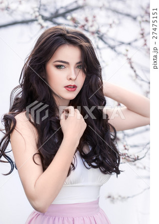 Beautiful girl standing at blossoming tree in the 27475151