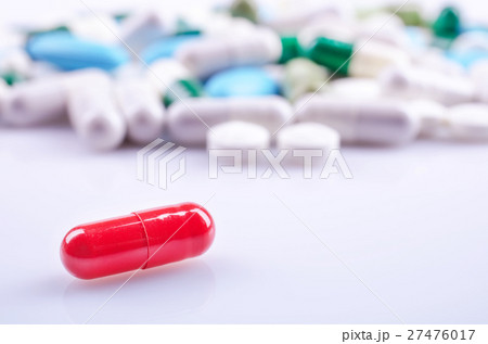 Red capsule closeup on a white surface Red capsule closeup on a white surface 27476017