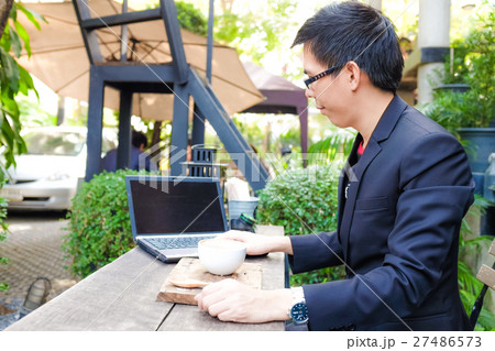Business man working on laptop with coffee cup Business man working on laptop with coffee cup 27486573